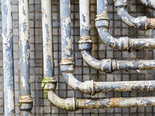 Licensed plumber in Weston FL inspecting old corroded pipes during a residential plumbing system upgrade